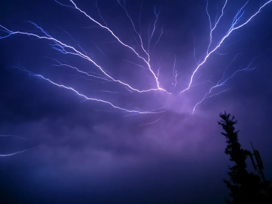 A bright lightning bolt striking down from a dark storm sky