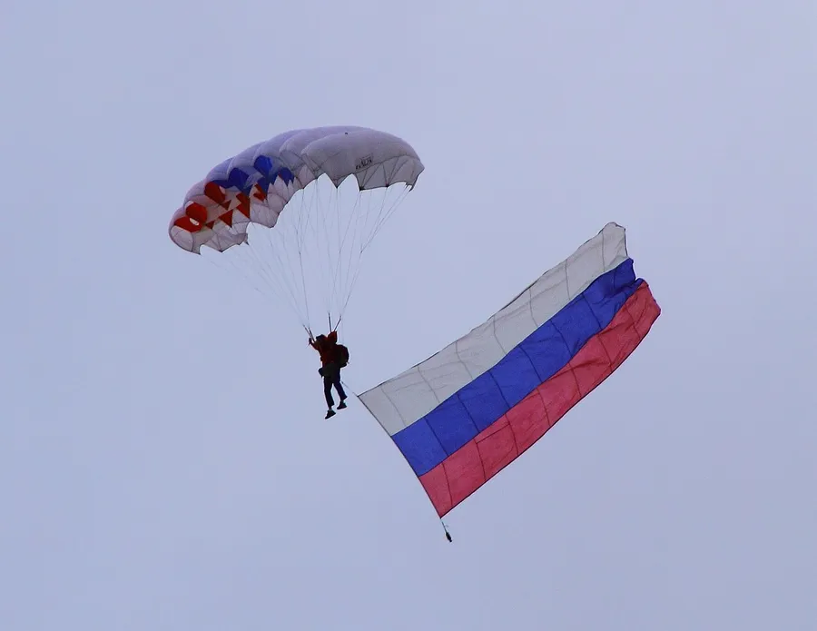 A skydiver drifting down under an open parachute slowed by air resistance