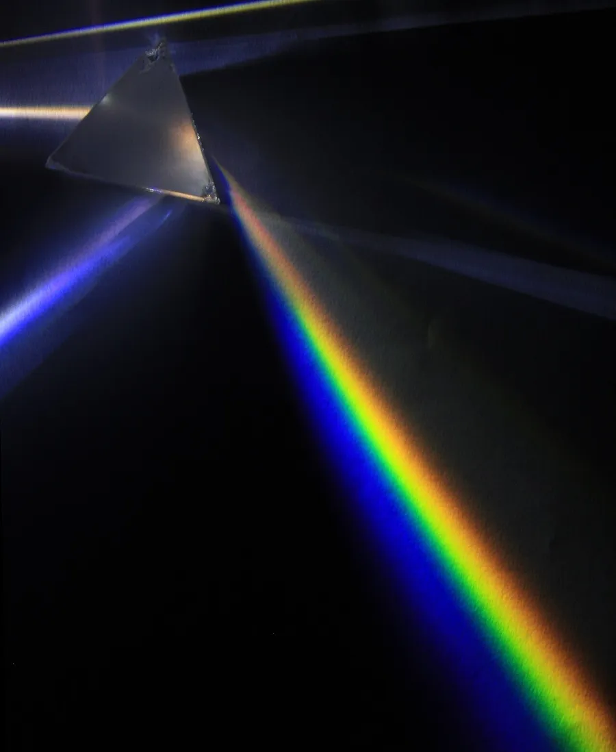 A glass prism splitting white light into a rainbow of colours