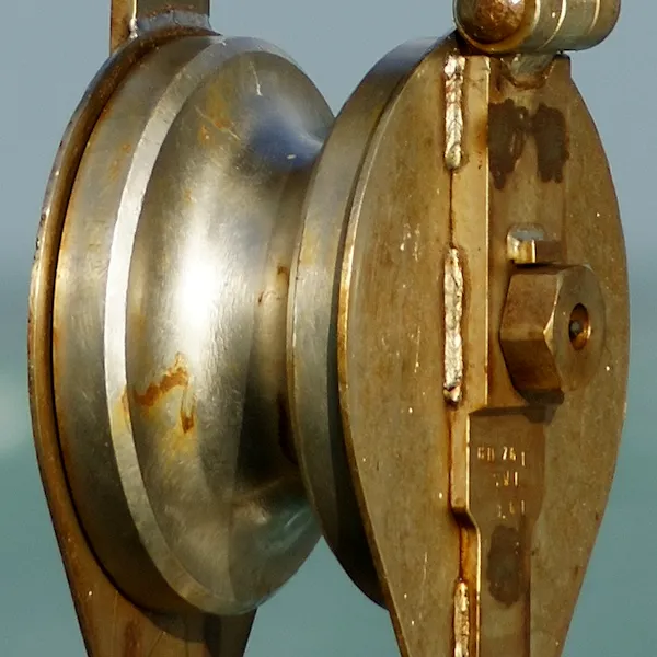 A rope running over a pulley wheel to lift a heavy load