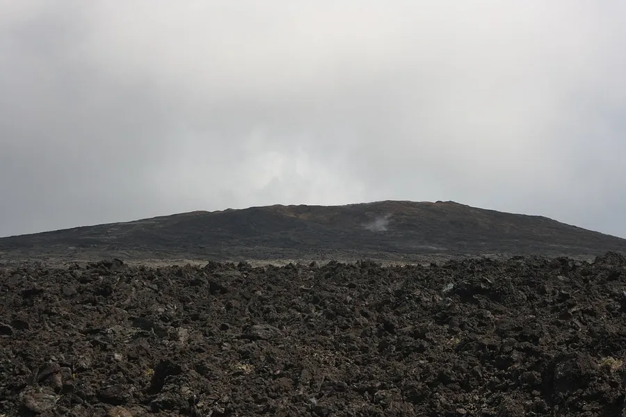 A wide, gently sloping shield volcano with runny lava flowing downhill