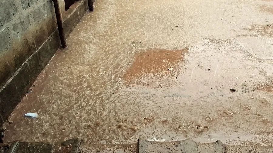 Heavy raindrops falling and splashing into puddles on the ground