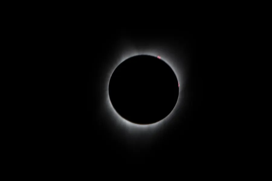The Sun's white corona glowing around the dark Moon during an eclipse